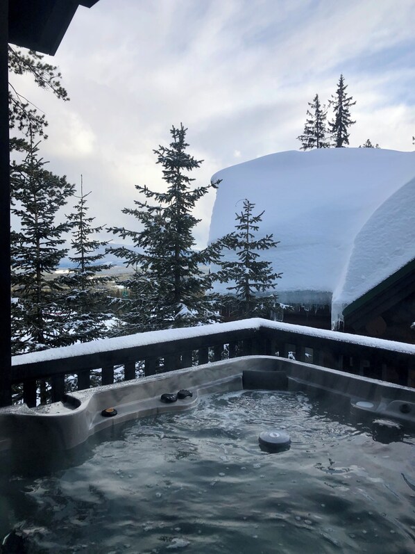 A hot tub area with snow-covered trees and a large snow-covered structure in the background.