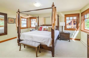 A four-poster bed with a canopy, a bedside table, a bench, and a nightstand.