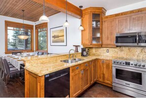 A kitchen with wooden cabinets, granite countertops, stainless steel appliances, and pendant lighting.