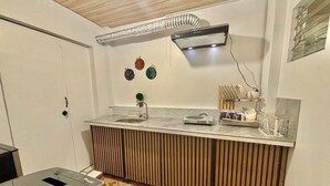 A compact kitchen with a built-in countertop, a wall-mounted air conditioner, and a small sink.