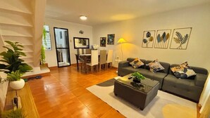 A modern living room with a sofa, coffee table, and dining area.