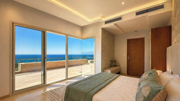 Ein Schlafzimmer mit einem großen Bett, Meerblick und einem Balkon.