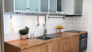 Una cocina moderna con armarios de madera, un lavamanos de acero inoxidable y un horno empotrado.