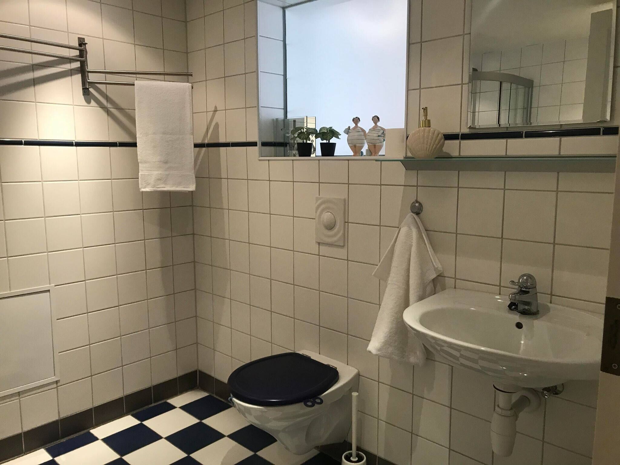 A bathroom with a toilet, sink, and a mirror.