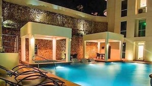 A pool area with lounge chairs and a stone wall. - Serene 1-Bedroom Apartment in Boracay with Pool Access (Boracay Island)