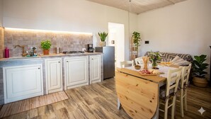 A modern kitchen with white cabinets, a wooden dining table, and a built-in oven. - Casa Nord Silvano - rustico di paese (Borghetto d'Arroscia)