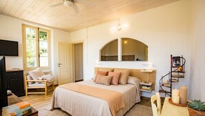 A bedroom with a bed, a chair, a TV, a bookshelf, and a window. - Casa Nord Silvano - rustico di paese (Borghetto d'Arroscia)