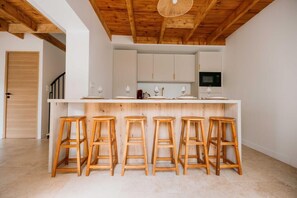 A kitchen with wooden stools, white cabinets, and a wooden ceiling. - Maison "Lomy" bord de mer- 2ch- Large enclosed garden (Pléneuf-Val-André)