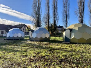 Drie koepelvormige constructies in een open landschap.