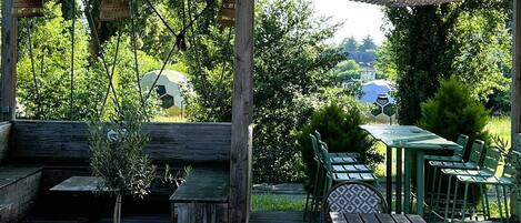 A wooden deck with outdoor seating, a pergola, and a view of a soccer field.