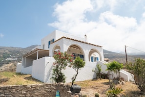 A white building with arched windows and a stone wall in front.