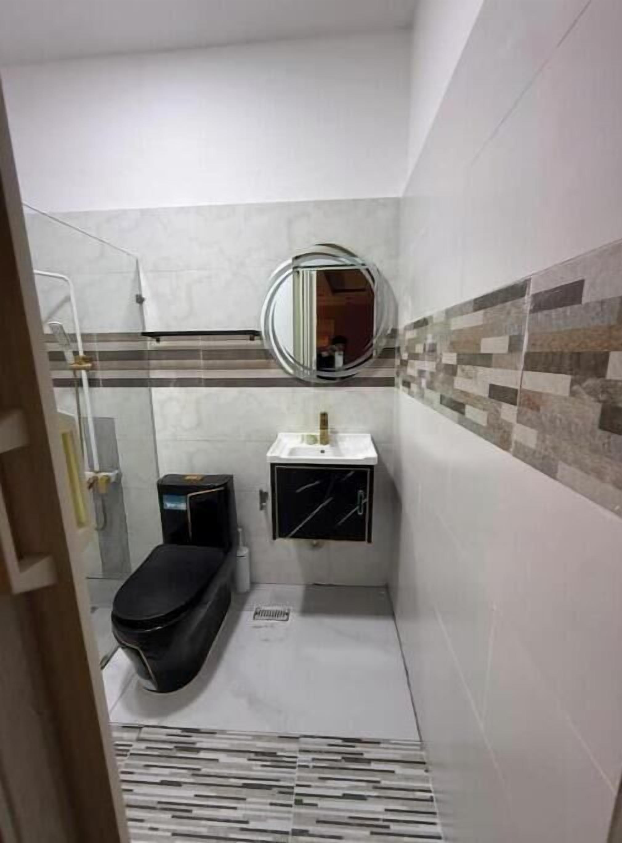 A small bathroom with a toilet, a sink, and a shower.