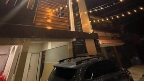 Un edificio con una escalera, luces colgantes y un vehículo al frente.