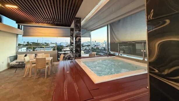 Terraza en la azotea con hidromasaje, zona de estar y vistas a la ciudad.