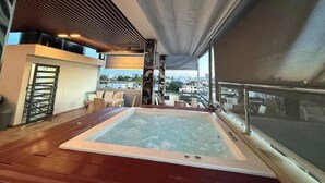 Una terraza en la azotea con un jacuzzi, zona de estar y vistas de la ciudad.