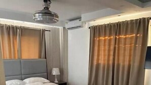 Ein Hotelzimmer mit Bett, Nachttisch, Klimaanlage und Deckenventilator.