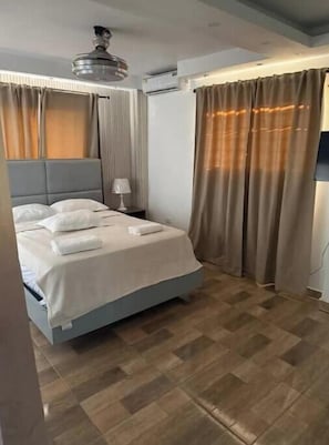 Ein Hotelzimmer mit Bett, Nachttisch, Klimaanlage und Deckenventilator.