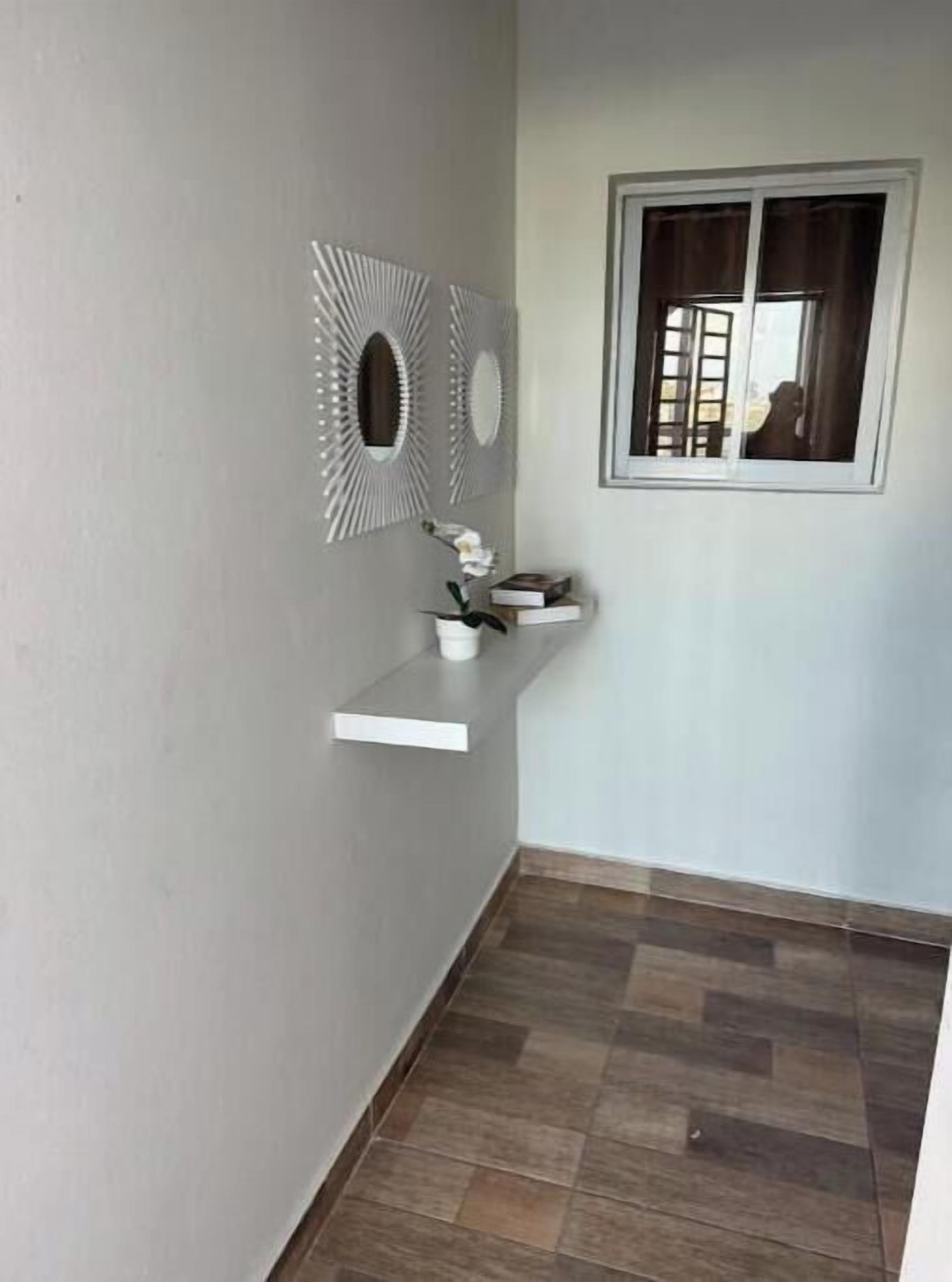A corner room with a built-in shelf, a window with curtains, and a decorative wall piece.