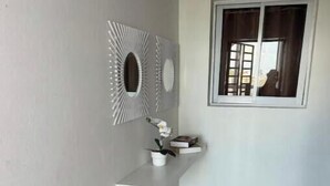 Ein Eckzimmer mit eingebautem Regal, einem Fenster mit Vorhängen und einer Wanddekoration.