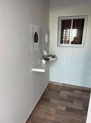 Ein Eckzimmer mit eingebautem Regal, einem Fenster mit Vorhängen und einer Wanddekoration.