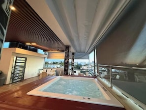 Eine Dachterrasse mit Whirlpool, Sitzgelegenheit und Blick auf die Stadt.