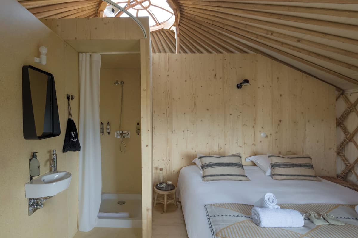 Una habitación de madera con una cama, un lavamanos y una ducha.