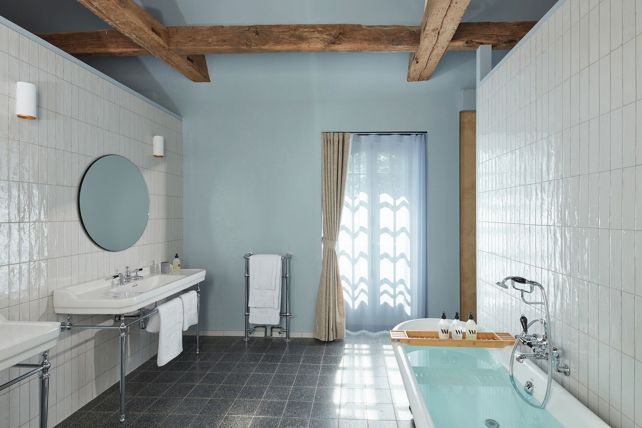 A bathroom with a bathtub, a sink, a mirror, and a towel rack.