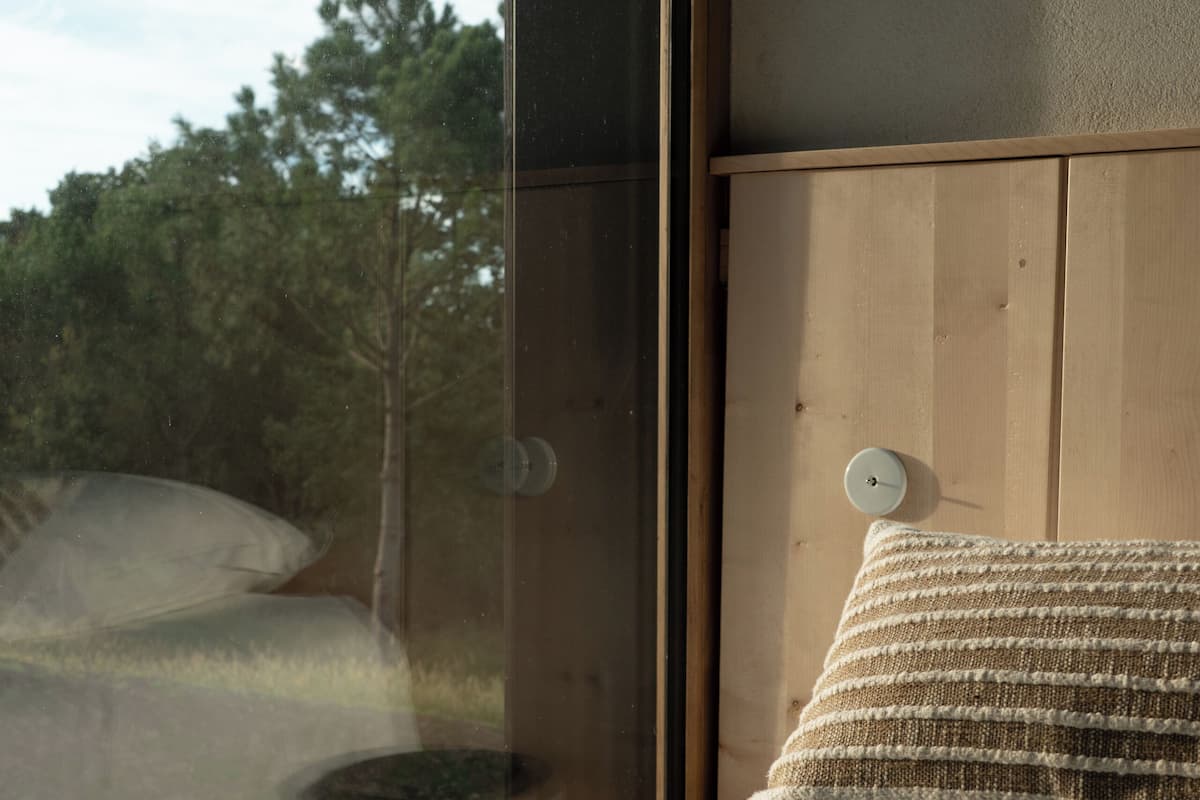 Un dormitorio con un ventanal grande, cabecera de madera y una sola almohada.