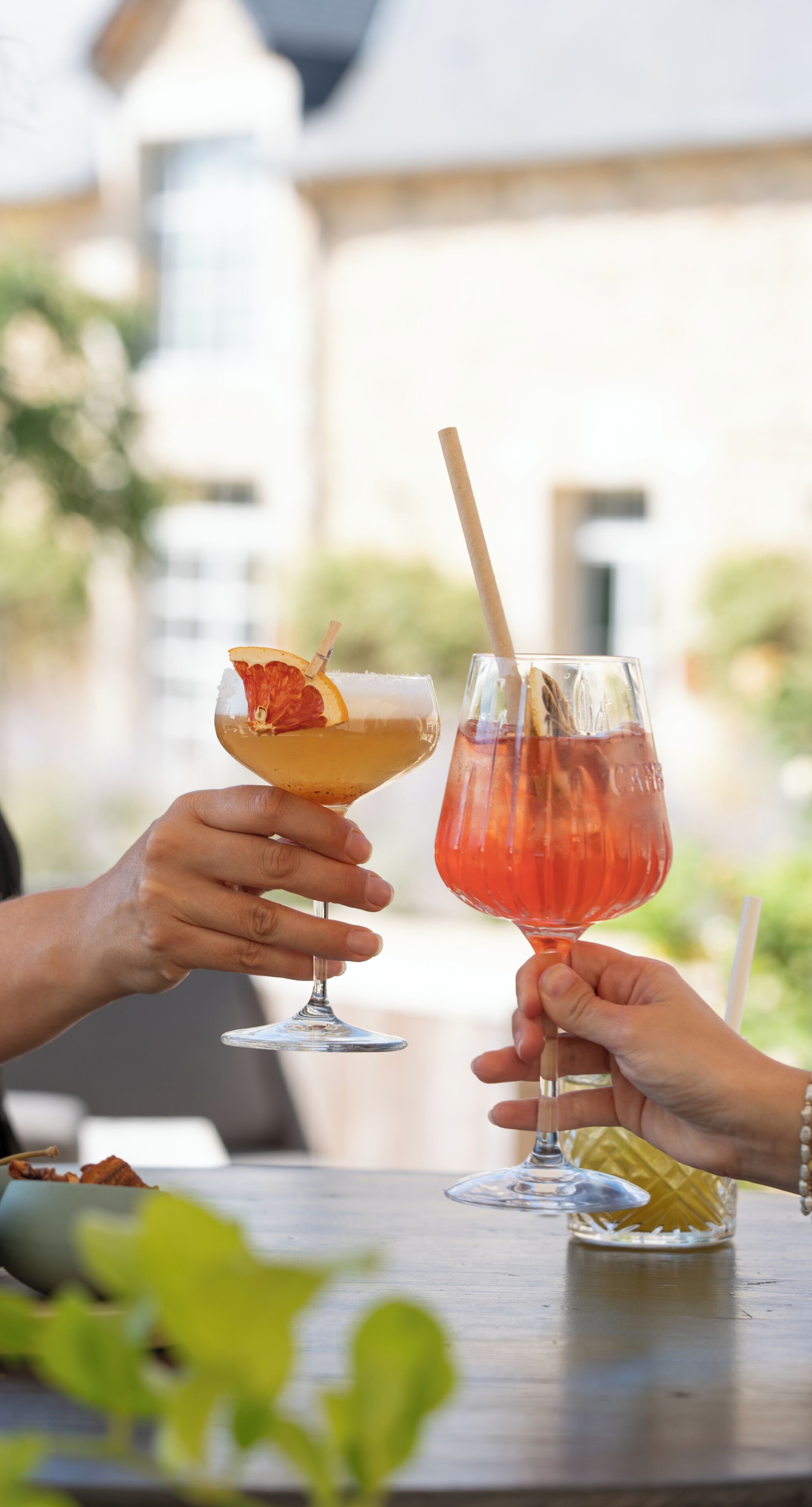 Two people holding drinks at a table with a building in the background.