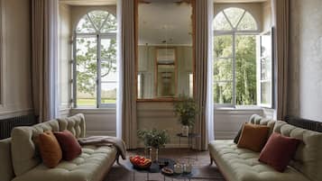 Une pièce avec deux canapés placés face à face, une petite table sur laquelle se trouve un saladier rempli de fruits, et un miroir au-dessus de la table.