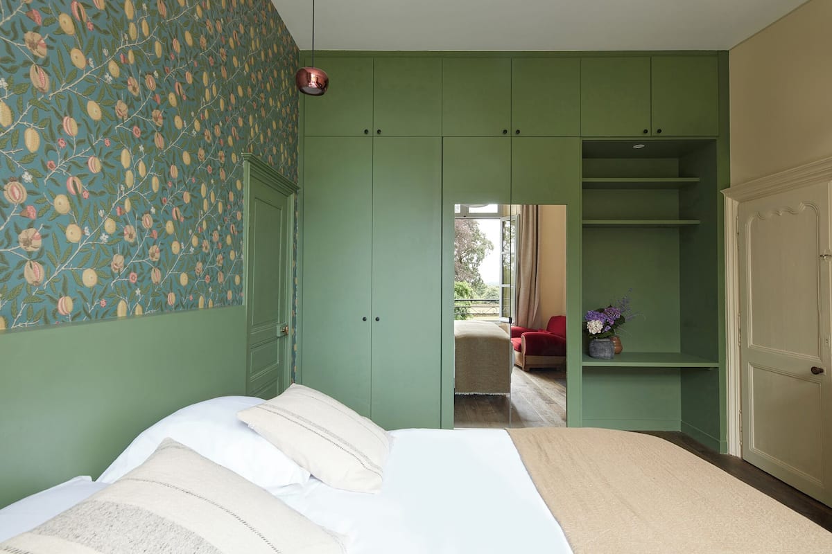 Un dormitorio con cama, armario verde y vistas al balcón.