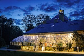 A greenhouse structure with a glass roof, surrounded by stone walls and a stone bench in the foreground. - Domaine Le Mezo (Ploeren)