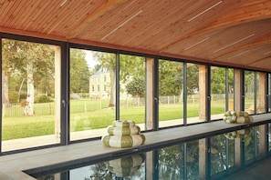 Une piscine dotée d’un plafond en bois et de grandes fenêtres.