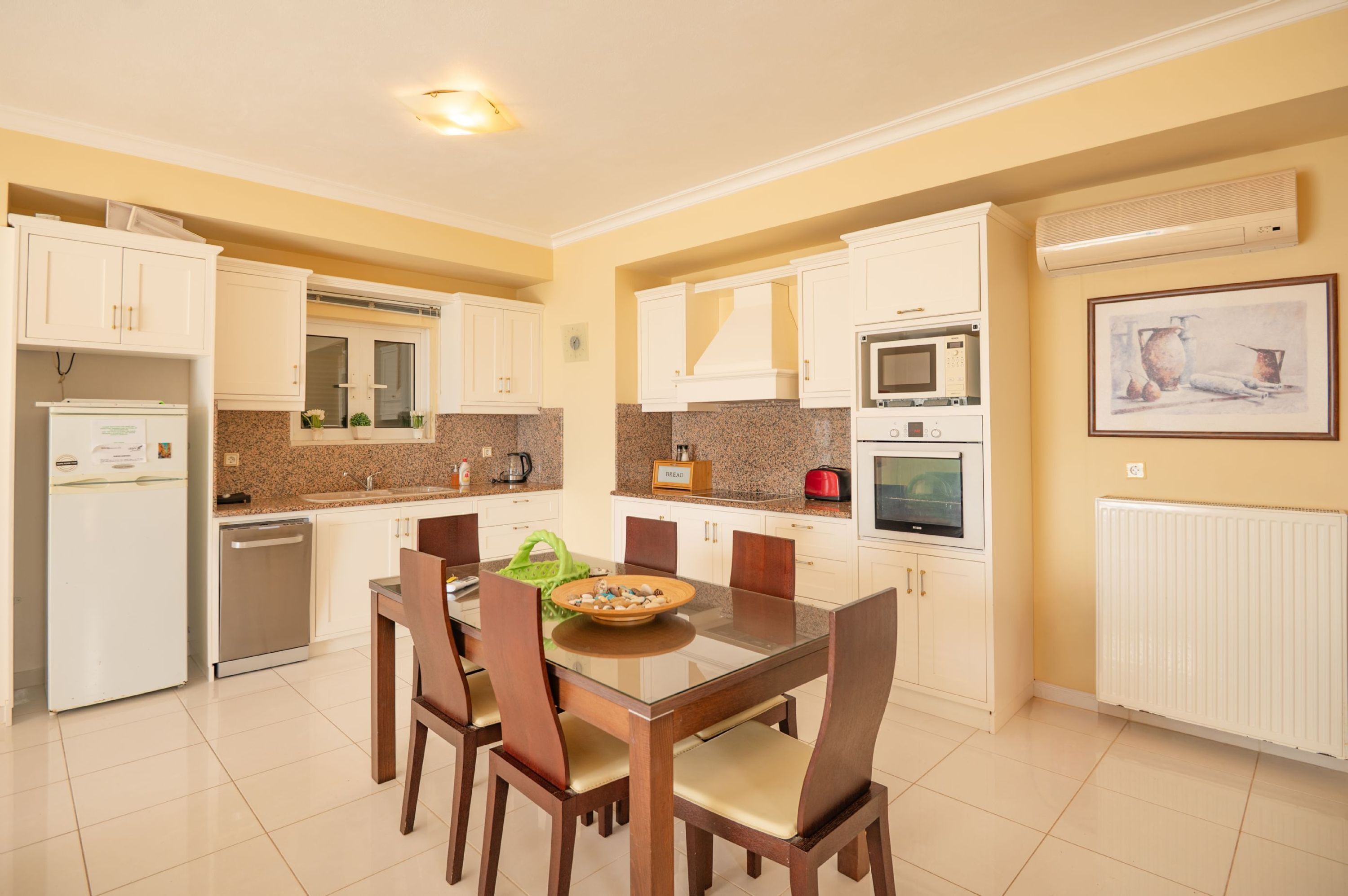 A modern kitchen with white cabinets, a granite countertop, and a dining table with chairs.