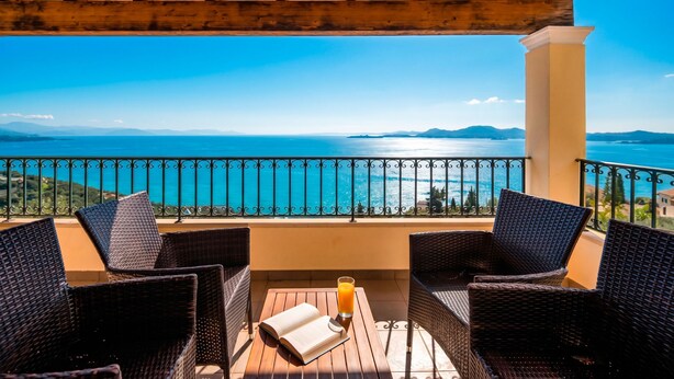 A balcony with wicker chairs, a table, and a glass of orange juice. - Villa Anastasia Viglatsouri (Corfu)