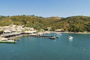 A coastal marina with boats docked, a pier, and buildings with a hillside backdrop. - Villa Anastasia Viglatsouri (Corfu)