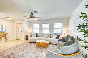 Ein Wohnzimmer mit einem Ecksofa, einem runden Couchtisch und einem Deckenventilator.
