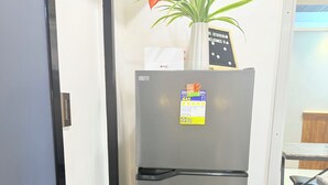 Ein Edelstahl-Kühlschrank mit Aufkleber, Topfpflanze und einem Schild darauf.