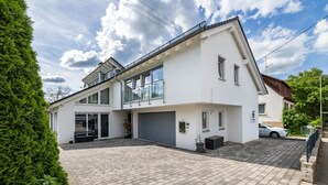 Une maison moderne à deux étages, dotée d’un garage, d’un patio couvert et d’un jardin bien entretenu.