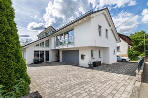 A modern two-story house with a garage, a covered patio, and a well-maintained garden.