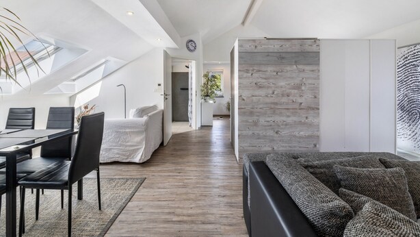 Un intérieur moderne comprenant un coin repas, un canapé, un mur d’accent en bois et une lucarne.