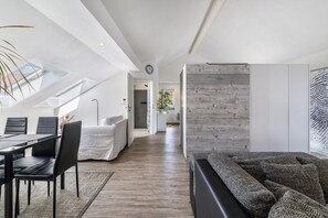 Ein modernes Interieur mit Essbereich, einer Couch, einer Wand aus Holzpaneelen und einem Oberlicht.