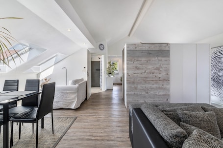 A modern interior with a dining area, a sofa, a wooden accent wall, and a skylight.. Apartment with Terrace, Garden & BBQ – Pets Welcome