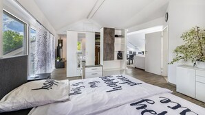 Une chambre moderne avec un grand lit, un dressing et une vue sur l’extérieur.