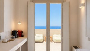 A compact kitchen with a view of the beach through a sliding door. - Vespera Private Luxury Suites (Santorini)