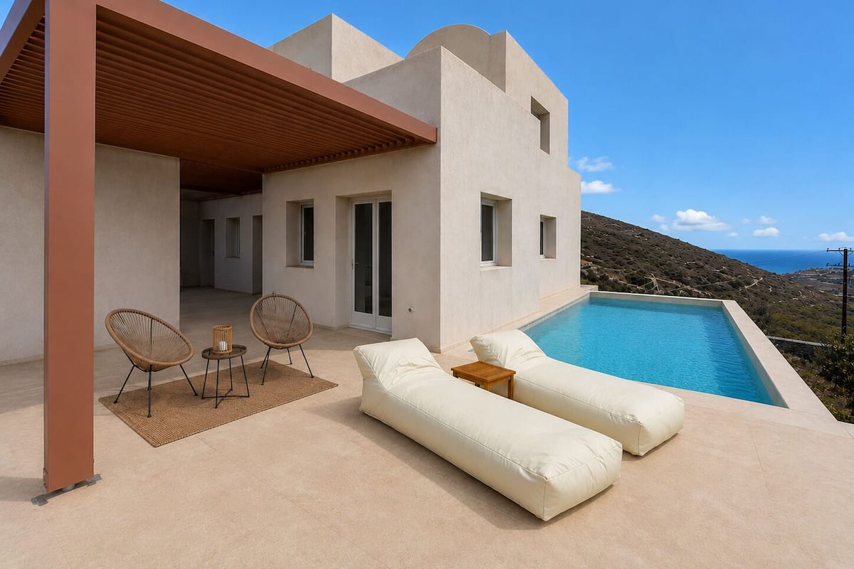 A modern villa with a pool, outdoor seating, and a view of the sea.