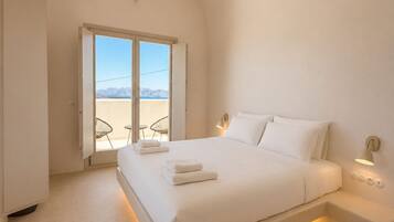 Un dormitorio moderno con una cama grande, una mesita de noche, una lámpara y vistas al exterior a través de una puerta.