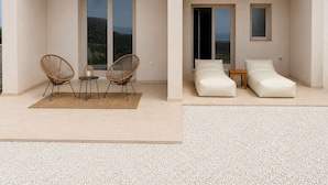 A modern outdoor living space with a seating area, two lounge chairs, and a table with a rug. - Vespera Private Luxury Suites (Santorini)