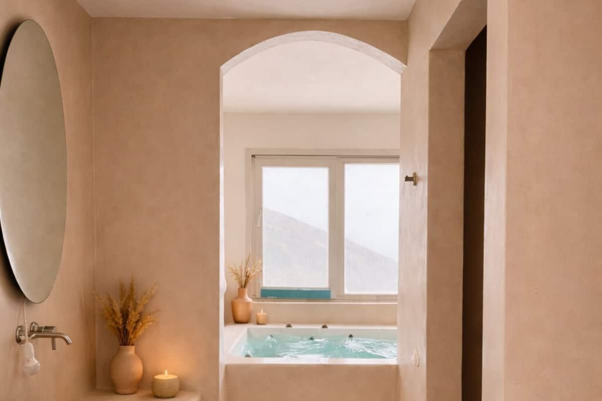 A bathroom with a large mirror, a sink, a bathtub, and a window overlooking a mountainous landscape.
