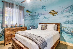 Un dormitorio con cama, cabecera de madera y un mural de peces y paisaje submarino en la pared.